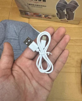 A white USB charging cable coiled in a person's hand, with a gray fabric sleeve and a cardboard product box visible in the background.