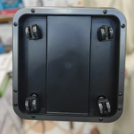 The underside of a black plastic appliance or furniture piece with four caster wheels, shown in a close-up view.